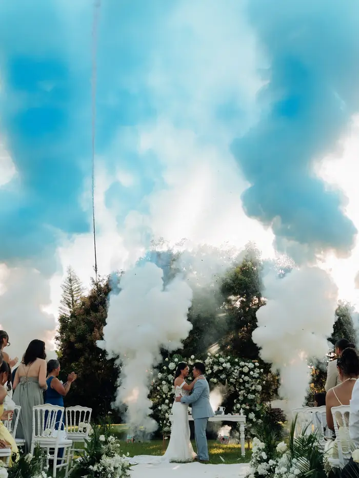 Ceremonia al aire libre con humo blanco y arco de flores