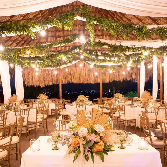 Terraza montada para un evento, con mesas, flores y luces colgantes