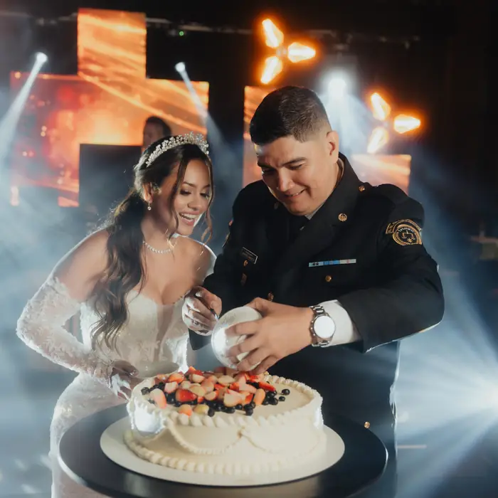 Novios cortando la torta bajo luces de colores